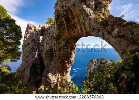 “Arco Naturale“ is a natural limestone arch that forms a bridge between two pillars of rock. It is located on the top of a cliff on Capri island Italy. Formation with mediterranean sea in background. Royalty-Free Stock Photo #2208376863