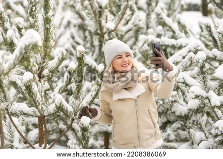 woman takes selfie in the snow covered forest during a winter adventure.