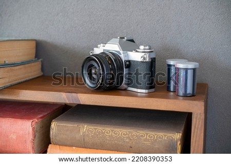 Old fashioned 35mm camera with slide film on bookshelf     Royalty-Free Stock Photo #2208390353