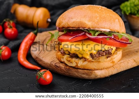 Tasty grilled home made burger with beef, tomato, cheese, onion and lettuce.