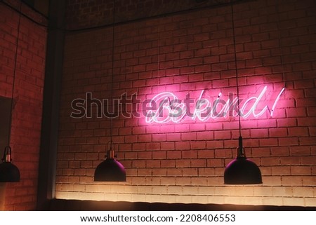 Neon sign of word BE KIND in the interior bar, Concept of relaxing outside and communication. Vintage toning, dark lights