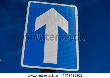 One way sign set against a blue sky