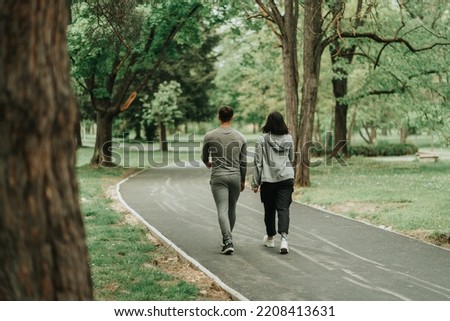 Sport couple walking on the path in the park Royalty-Free Stock Photo #2208413631