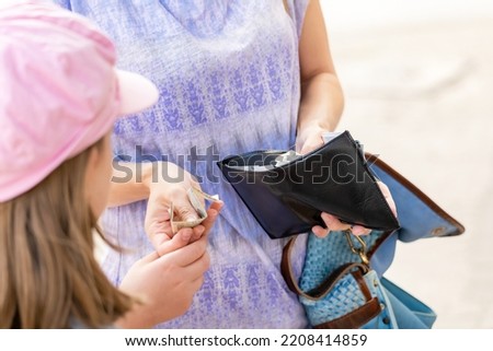 Anonymous mother giving her child money, hands closeup, wallet, receiving pocket money, giving kids money, monthly allowance simple concept. Children, small family finance management, people lifestyle Royalty-Free Stock Photo #2208414859