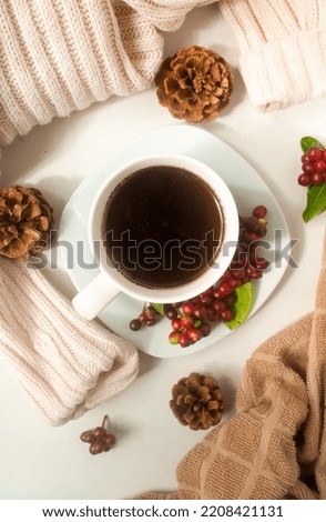 cup of coffee in a white plate, a beige jacket, flowers and a pine cone on a white background 