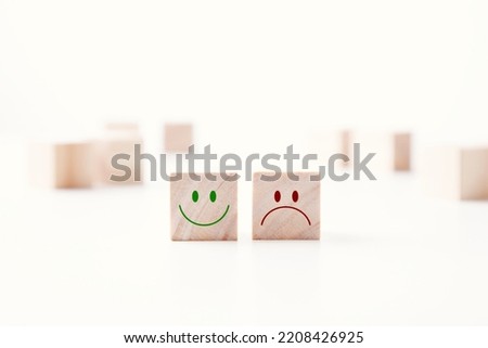 Smile face and sad face on wooden blocks on table white background. Mental health and emotional state concept. COPY SPACE.