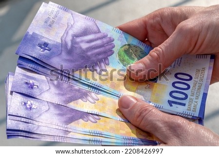 hands holding a stack of swiss francs money Royalty-Free Stock Photo #2208426997
