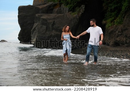 Happy young couple walking on beach near sea. Space for text
