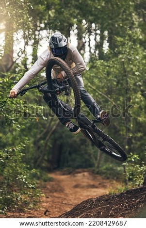 Sports, adventure and forest with man and mountain biking on park trail for action, freedom and fitness. Jump, speed and fast with athlete training in nature for exercise, health and workout Royalty-Free Stock Photo #2208429687
