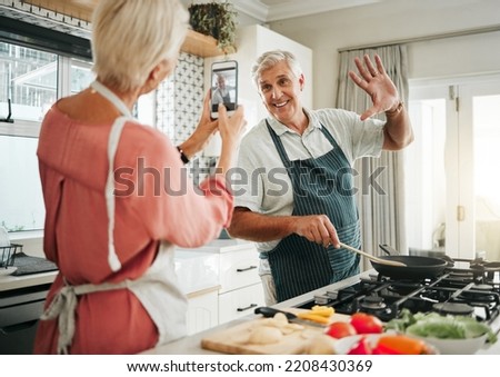 Phone, cooking and photograph with a senior couple in the kitchen recording a video while preparing breakfast food. Mobile, love and fun with an elderly man and woman pensioner in the house together