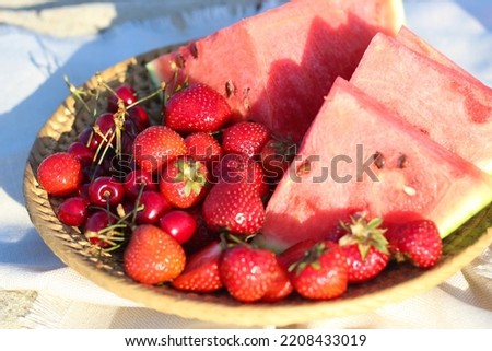 Fruit tray with strawberries and cherries on a picnic on the beach.
