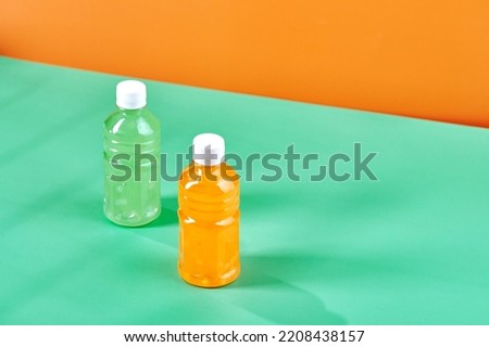 Two small bottles with colorful drinks on color background