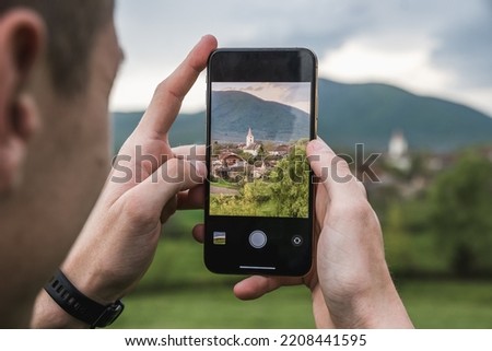 Young man is taking picture of the village by his smartphone