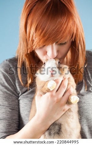 Young woman kissing her cute bunny pet.