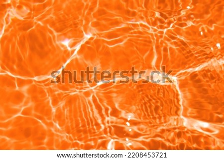 Defocus blurred transparent orange colored clear calm water surface texture with splash, bubble. Shining orange water ripple background. Surface of water in swimming pool. Orange bubble water shine.