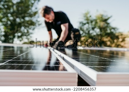mature Technician man assembling solar panels on house roof for self consumption energy. Renewable energies and green energy concept. focus on foreground Royalty-Free Stock Photo #2208456357