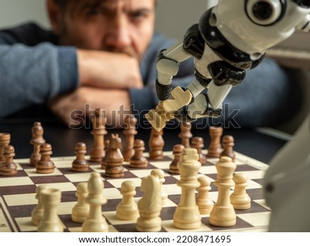 A man plays chess with a robot. The concept of man versus robot. Royalty-Free Stock Photo #2208471695