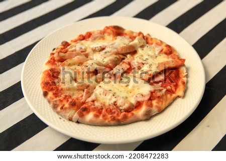 Top view VERY HOT Italian Pizza on white plate  with ham ,sausage , mushrooms, tomato and cheese.