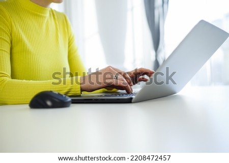 Girl typing text on laptop keyboard at home. Young woman working on modern notebook pc. Download stock photo of female programmer coding on portable computer