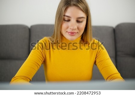 Beautiful blonde girl working on a computer at home with a smile