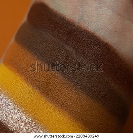 Eye shadow swatches, dry powder, set of autumn winter colorful brush strokes on skin. Cosmetic makeup texture samples, smear trace samples on colorful background. Realistic photography