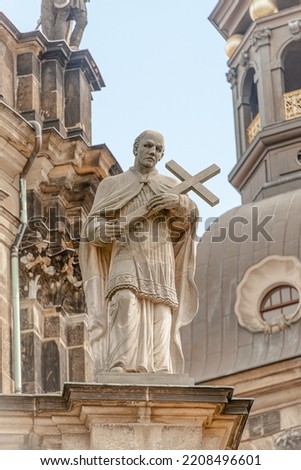 Old roof statute of priest or monk holding a big cross at Dome base of the Cathedral of Holy Trinity, historical center of Dresden, Germany