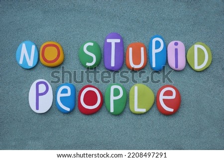 No stupid people, creative slogan composed with multi colored stone letters over green sand