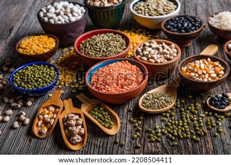 Vegan protein source.Various assortment of legumes, lentils, chickpea and beans assortment in different bowls on wooden table. Top view. Royalty-Free Stock Photo #2208504411