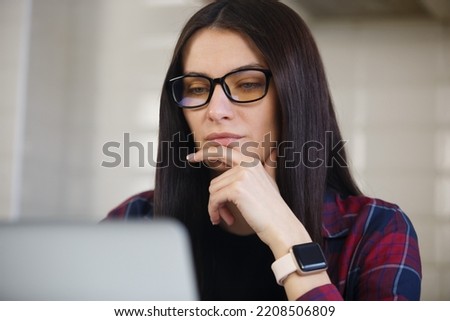 Freelancer woman thinking about problem solution. Young entrepreneur person working on computer. Brunette girl in glasses works on laptop. Download stock photo of freelance professional at work