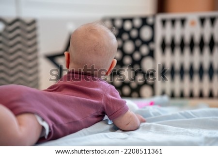 Rear view of the baby lying on his tummy and looking at black and white pictures