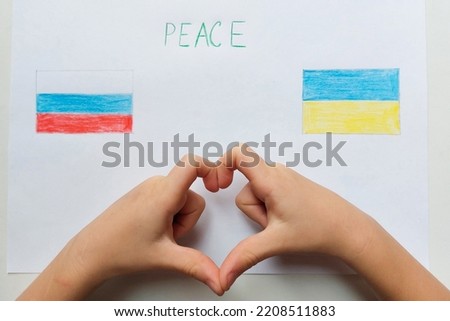 Concept of the end of war in Ukraine. Selective focus. Children's fingers folded in the shape of heart. Children's drawing of flags of Russia and Ukraine. Inscription peace. High quality photo