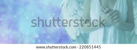 Cropped Angel showing torso in white robes with hands held over heart on a misty blue bokeh background with copy space on left hand side