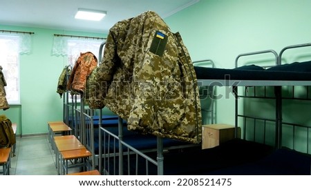 Barracks in the Ukrainian army. The Soldiers' Room has bunk beds. Military uniforms hang on the beds. Ukraine is defending its territory from a Russian attack. Real War 2022  Royalty-Free Stock Photo #2208521475
