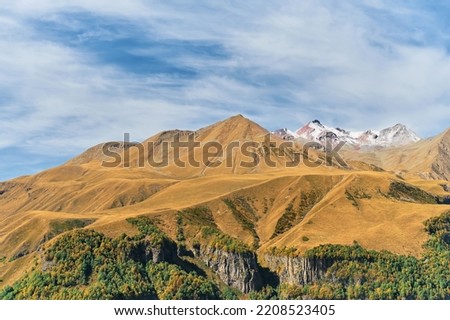 Autumn in the mountains, high sky with clouds, snow-capped mountain peaks. Banner with space for text, trip to Georgia, trekking in the mountains