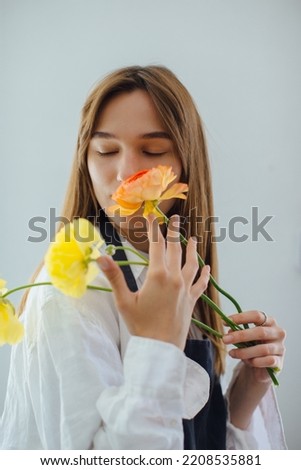 Woman smelling flowers while arranging it at flower shop - stock photo
