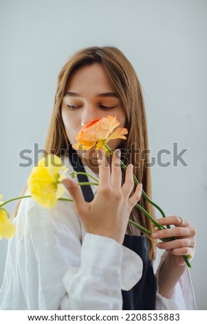 Woman smelling flowers while arranging it at flower shop - stock photo
