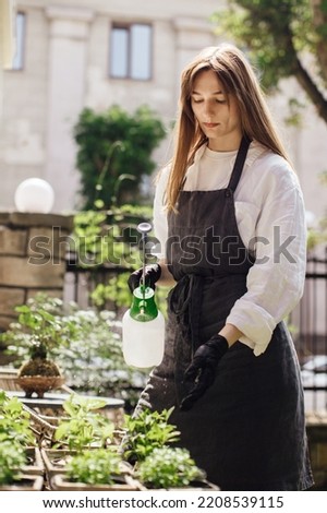 Woman florist watering plants in a flower shop - stock photo.