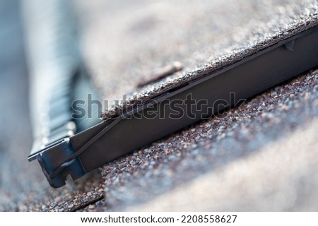 Ridge cap vent installed on a shingle roof for passive attic ventilation on a residential house.  Royalty-Free Stock Photo #2208558627