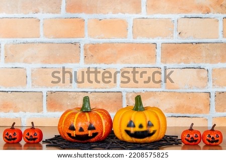 Two large jack-o'-lanterns on a brick background with a smaller jack-o'-lantern on the side