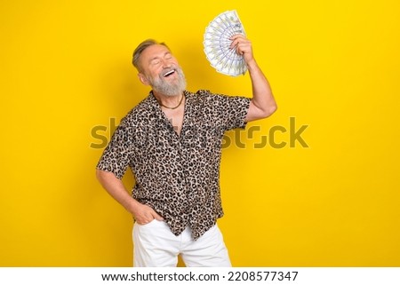 Photo portrait of handsome granddad wave banknotes fan hot weather wear trendy leopard print look isolated on yellow color background