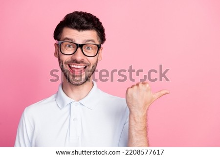Closeup photo of young attractive handsome positive bearded man wear white polo eyeglasses toothy finger pointing empty space new ad isolated on pink color background