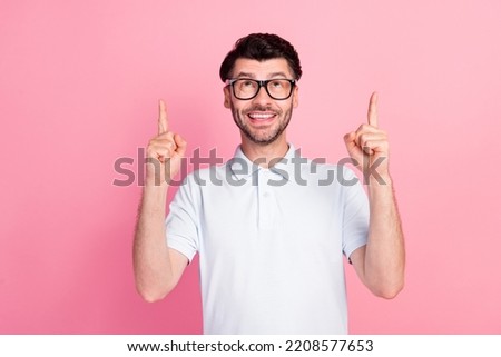 Photo of young funny excited positive handsome bearded man wear eyeglasses pointing fingers up look new information isolated on pink color background