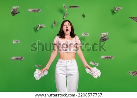 Photo of cheerful shocked girl dressed print blouse winning dollars prize isolated green color background
