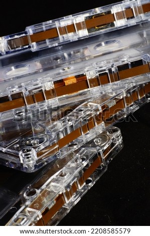 Cassette tapes - close-up, unprinted, with magnetic tape exposed, black background.