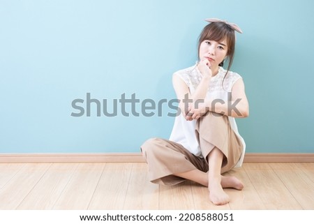 Asian woman sitting on wooden floor Royalty-Free Stock Photo #2208588051