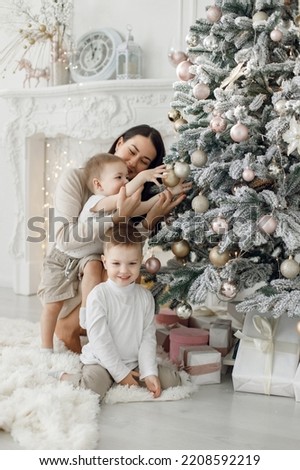 Young family in white clothes decorating the Christmas tree at home