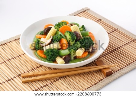 Vegan food ,Stir-Fried Vegetables ,vegetarian dish with mix of vegetables in plate on bamboo place mat on white background. Royalty-Free Stock Photo #2208600773