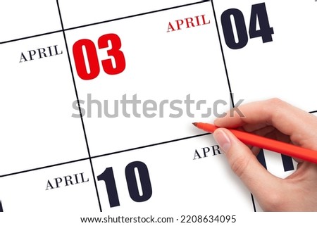 3rd day of April. A hand holding a red pen and pointing on the calendar date April 3. Red calendar date, copy space, mockup. Spring month, day of the year concept. Royalty-Free Stock Photo #2208634095