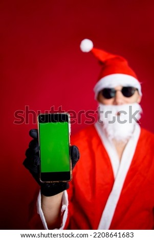 Portrait of handsome cheerful Santa father demonstrating device gadget display cellular 5g service sale isolated over bright vivid shine vibrant red color background
