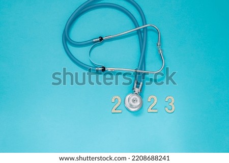 Medical stethoscope in a red Santa Claus hat and the numbers 2023 on a blue background. Christmas and New Year concept. Creative medical winter background, postcard. close